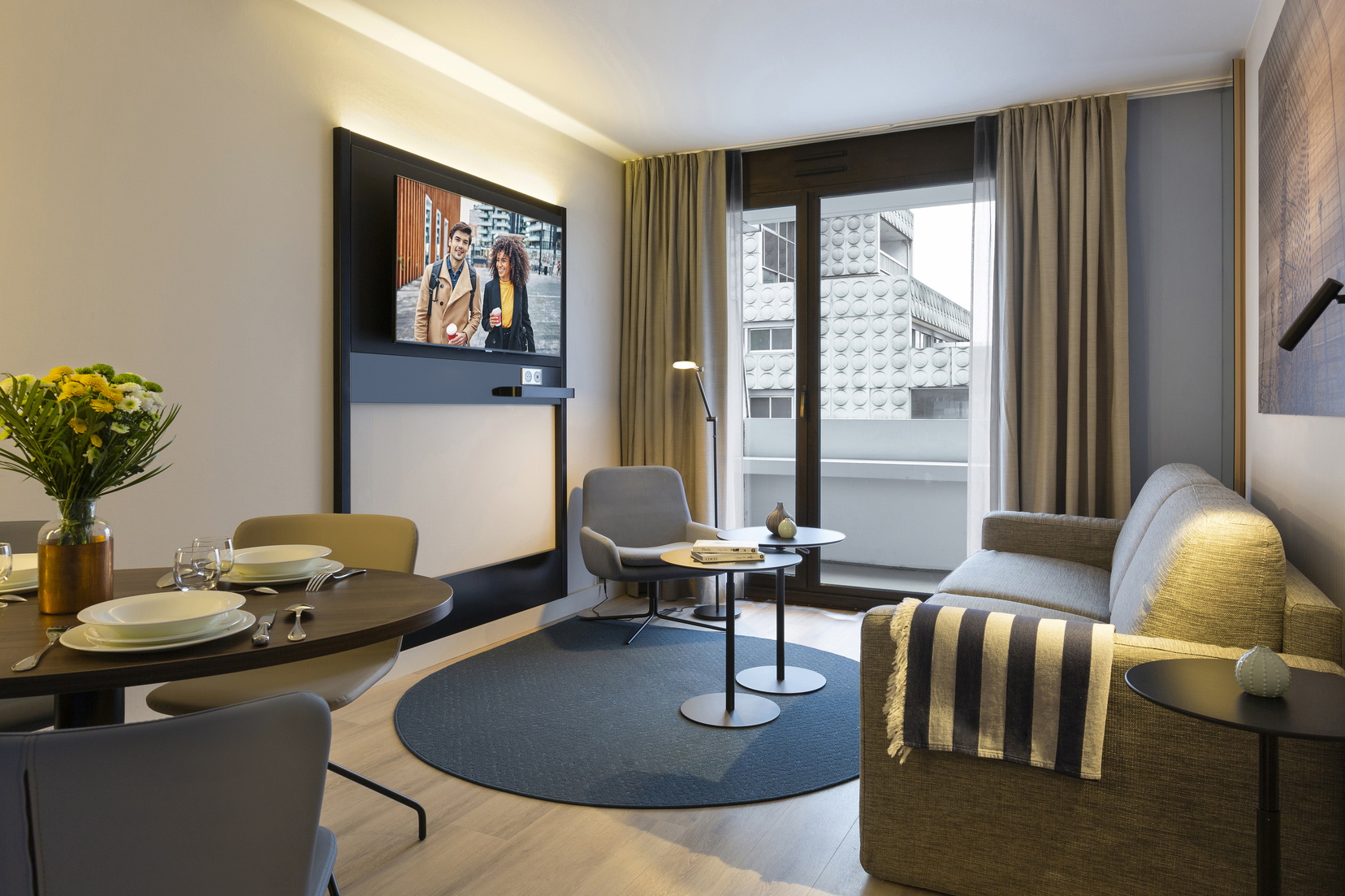 Living room of a 1-Bedroom Apartment Deluxe with Balcony equipped with a sofa bed and a dining area, apart hotel Paris la Défense