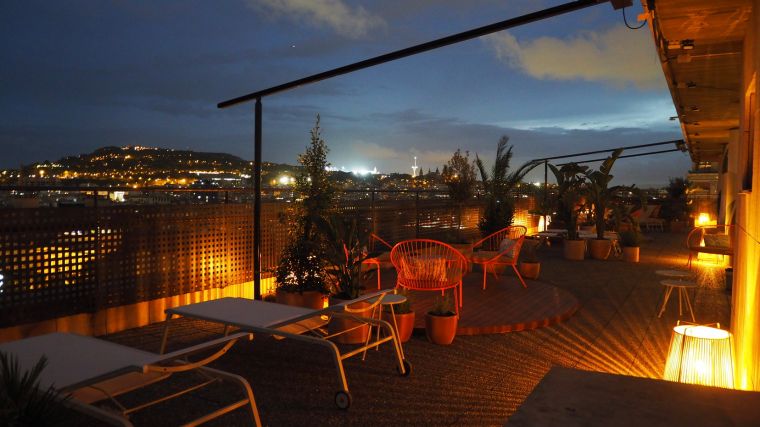 Terrace with sun loungers, sofas and wicker chairs with panoramic views of Barcelona, apart hotel Barcelona