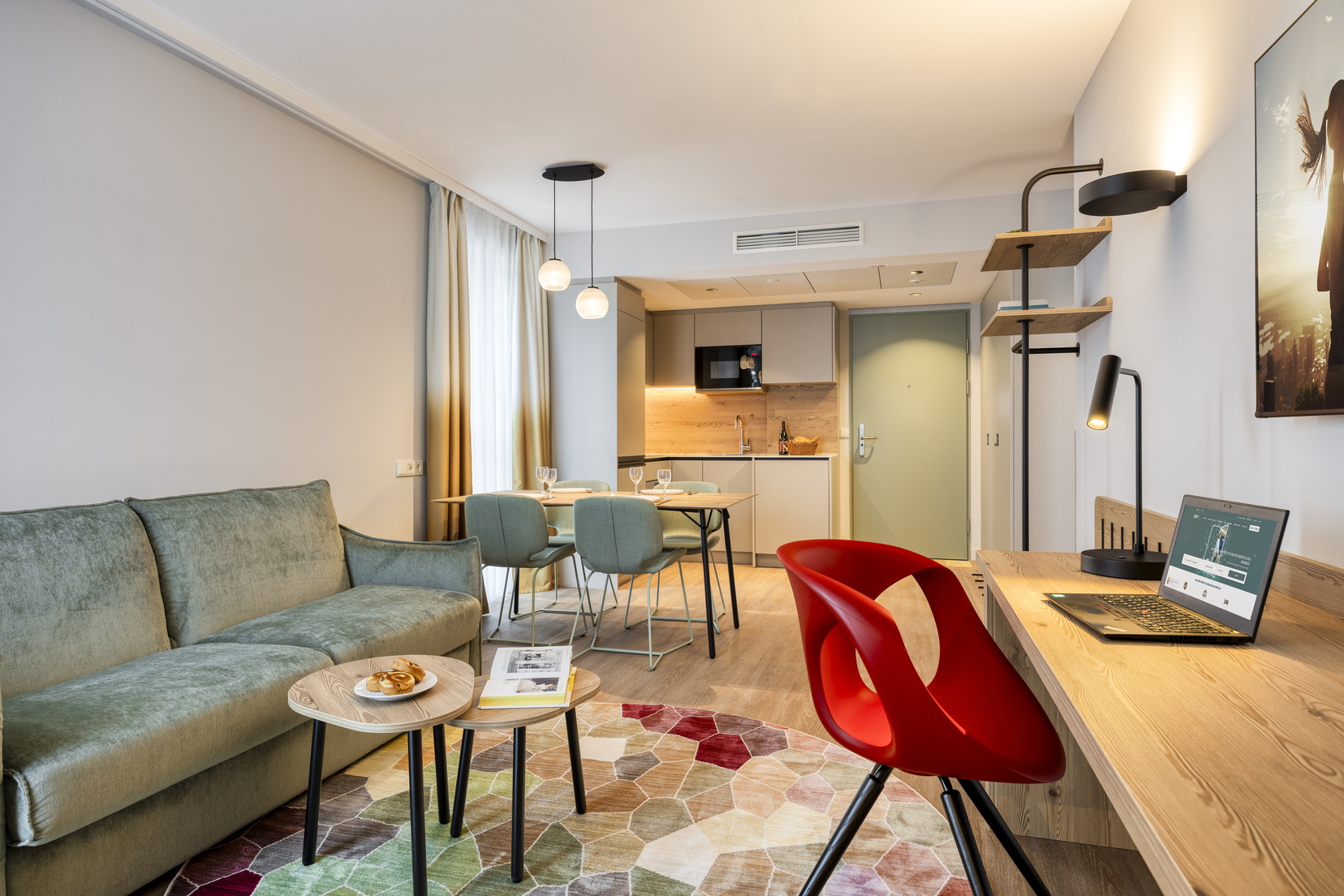 Living room of a One-Bedroom Executive Apartment with a sofa bed, desk, dining area, and fully equipped kitchen