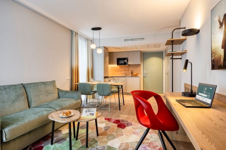 Living room of a One-Bedroom Executive Apartment with a sofa bed, desk, dining area, and fully equipped kitchen