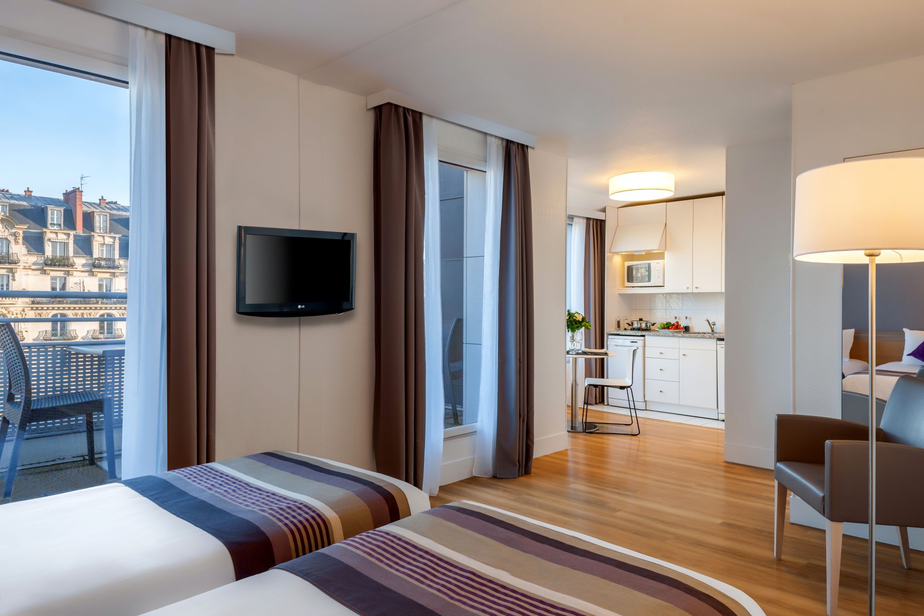 Studio Deluxe ausgestattet mit zwei Einzelbetten, einem Fernseher und einem Küchenbereich, wohnen auf Zeit in Paris 11