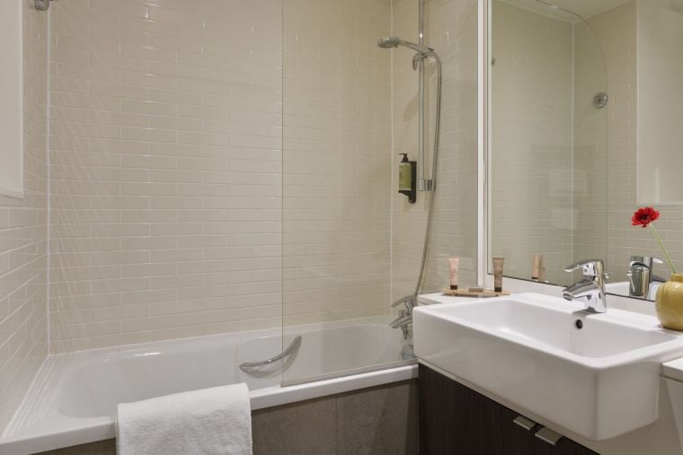 Salle de bain d'une Chambre Classique équipée d'un combiné baignoire/douche et de serviettes, appart hotel Paris 14