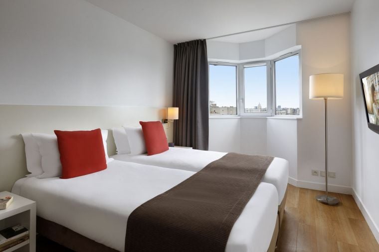 Chambre d'un Appartement 2 pièces équipée de deux lits simples et d'une télévision, appart hotel Paris 14