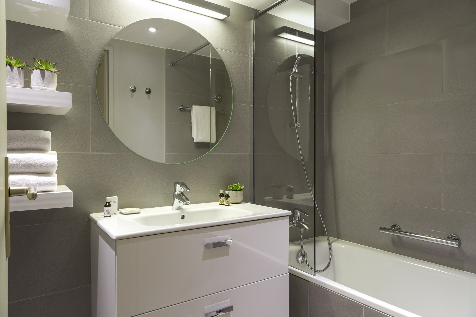Salle de bain d'un Studio équipée d'un combiné baignoire/douche, articles de toilette et serviettes, appart hotel Paris 13